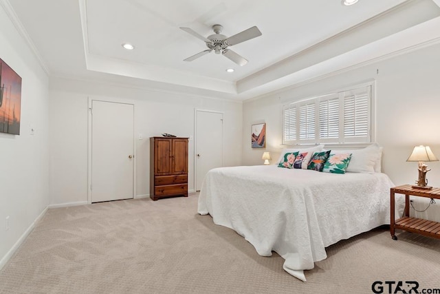 bedroom with light carpet, baseboards, a tray ceiling, and crown molding