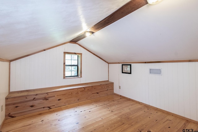 additional living space featuring wood-type flooring, lofted ceiling, and wood walls