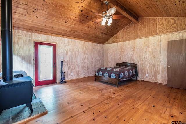 bedroom featuring wood ceiling, wooden walls, hardwood / wood-style floors, vaulted ceiling with beams, and a wood stove