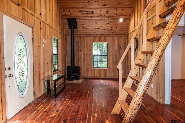 foyer with a wood stove, wooden walls, dark hardwood / wood-style flooring, and wooden ceiling