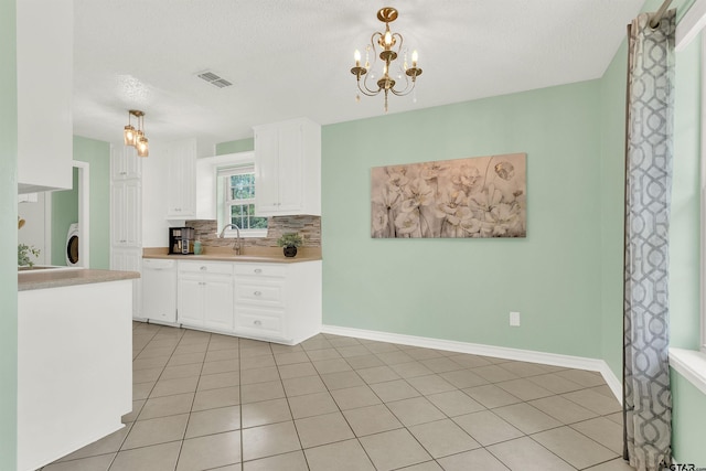 8811 Pheasant Dr, Chandler, TX 75758 - kitchen with dishwasher, white cabinets, backsplash, light countertops, and a chandelier