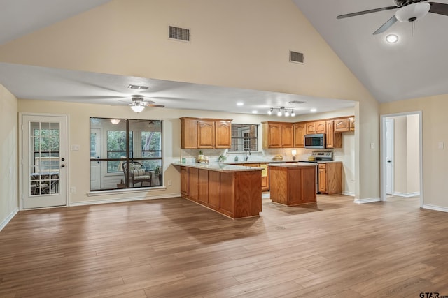 411 Raton, Holly Lake Ranch, TX 75765 - kitchen with stainless steel microwave, a ceiling fan, brown cabinetry, a peninsula, and high vaulted ceiling