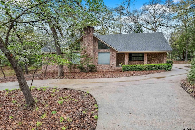 411 Raton, Holly Lake Ranch, TX 75765 - view of front facade with a chimney, a shingled roof, curved driveway, and brick siding