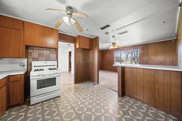 kitchen featuring visible vents, white gas range oven, a ceiling fan, and brown cabinets