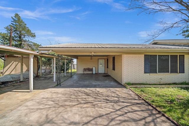 exterior space featuring metal roof, concrete driveway, brick siding, and a carport