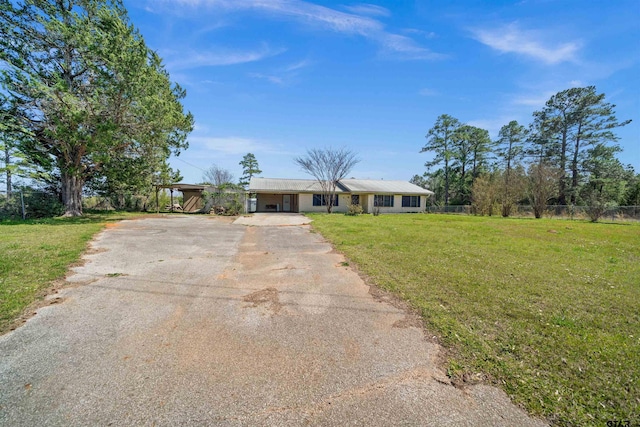 ranch-style home with aphalt driveway, fence, and a front lawn