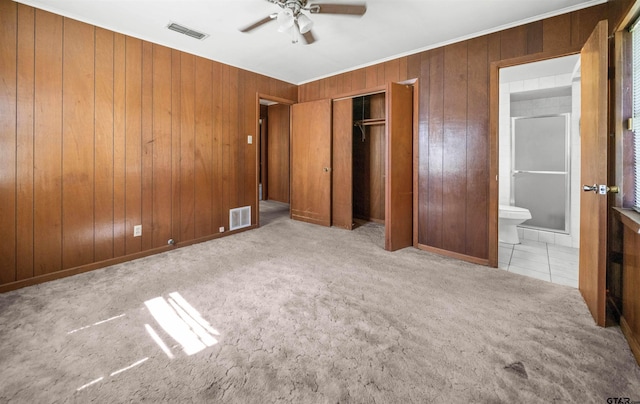 unfurnished bedroom featuring carpet flooring, visible vents, and wood walls