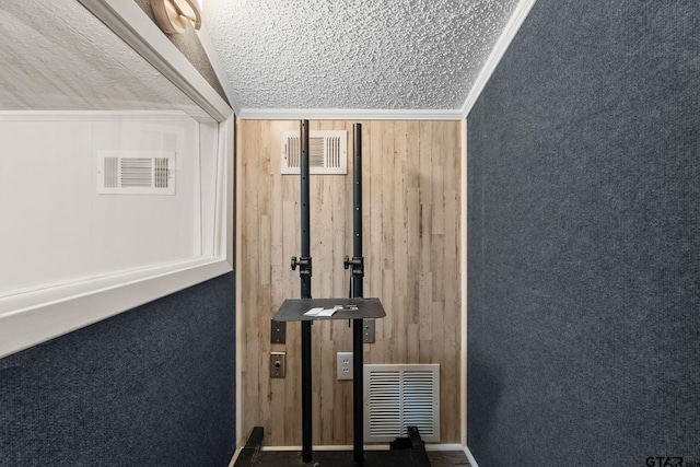 exercise area with vaulted ceiling, wooden walls, crown molding, and a textured ceiling