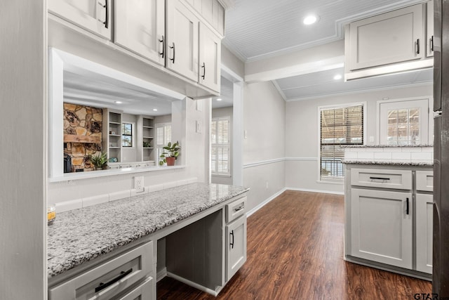 kitchen featuring built in desk, dark hardwood / wood-style floors, light stone counters, and ornamental molding