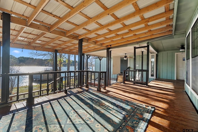 unfurnished sunroom featuring ceiling fan and a water view