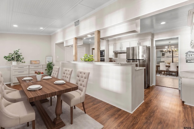 dining space with crown molding, dark wood-type flooring, and a notable chandelier