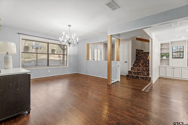 dining area featuring a notable chandelier, built in shelves, and dark hardwood / wood-style flooring