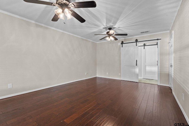 empty room with a barn door, dark hardwood / wood-style floors, and crown molding