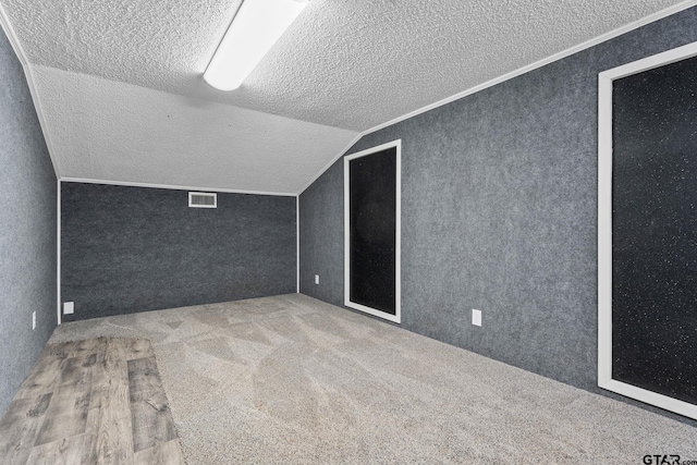 bonus room with lofted ceiling and a textured ceiling