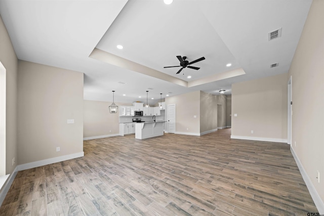 16221 Crossing Cir, Lindale, TX 75771 - unfurnished living room featuring a tray ceiling, a ceiling fan, recessed lighting, and light wood-style flooring