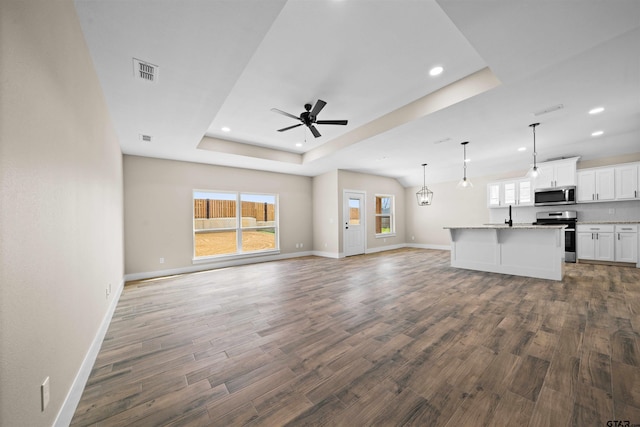 16221 Crossing Cir, Lindale, TX 75771 - unfurnished living room featuring a tray ceiling, plenty of natural light, wood finished floors, a ceiling fan, and recessed lighting