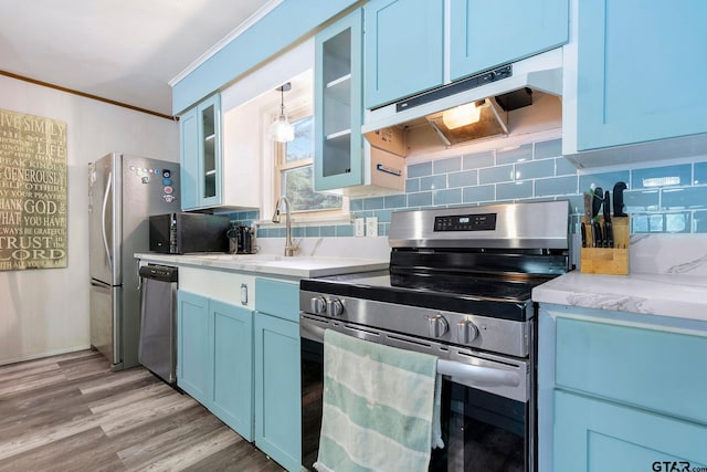 488 Omaha Dr, Omaha, TX 75571 - kitchen with stainless steel appliances, blue cabinetry, ornamental molding, backsplash, and glass insert cabinets