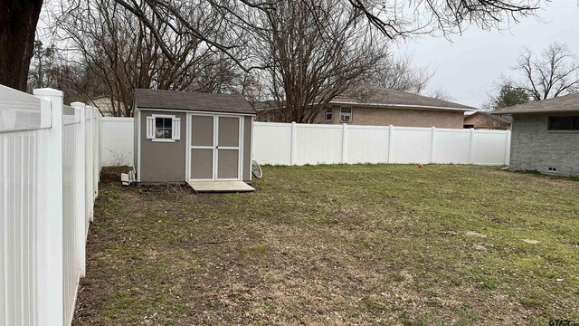 view of yard with an outbuilding, a shed, and a fenced backyard