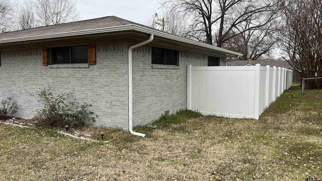 view of side of home featuring fence and brick siding