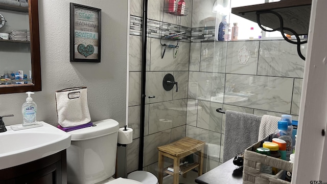 bathroom with a textured wall, a stall shower, vanity, and toilet