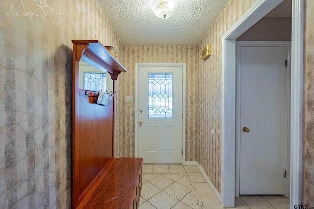 doorway to outside featuring wallpapered walls, baseboards, a textured ceiling, and light tile patterned flooring