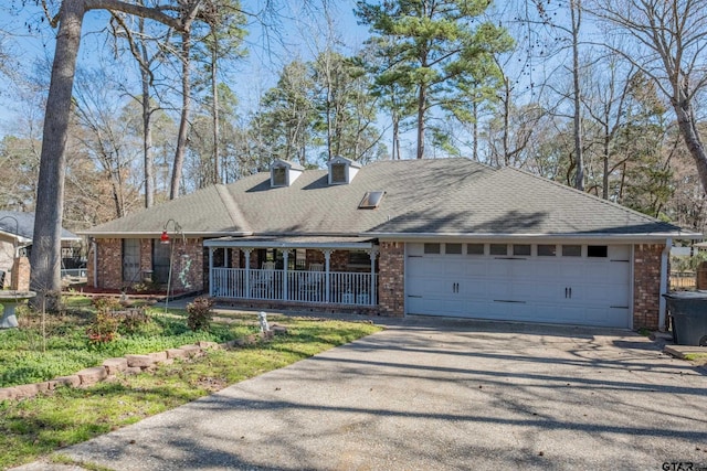 view of front facade with a garage, covered porch, aphalt driveway, and brick siding