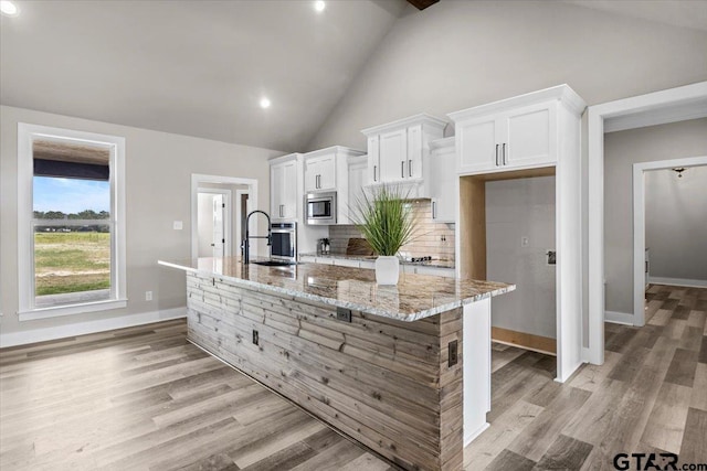 kitchen featuring white cabinets, sink, a large island with sink, and stainless steel appliances