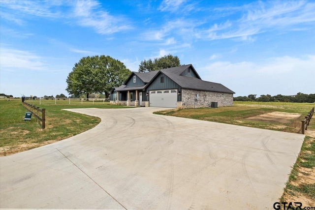 view of front of home with a garage, a rural view, and a front lawn