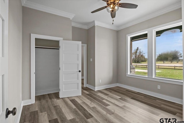 unfurnished bedroom with hardwood / wood-style floors, ceiling fan, a closet, and crown molding