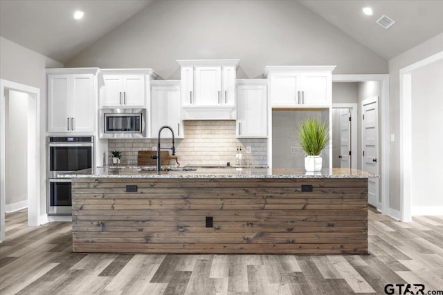 kitchen featuring light stone counters, appliances with stainless steel finishes, decorative backsplash, sink, and white cabinets