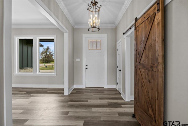 entryway featuring dark wood-type flooring, a chandelier, a barn door, and ornamental molding