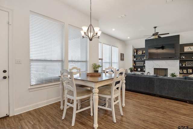9157 Teal Flight Way, Tyler, TX 75703 - dining space featuring wood finished floors, baseboards, a ceiling fan, a fireplace, and a chandelier