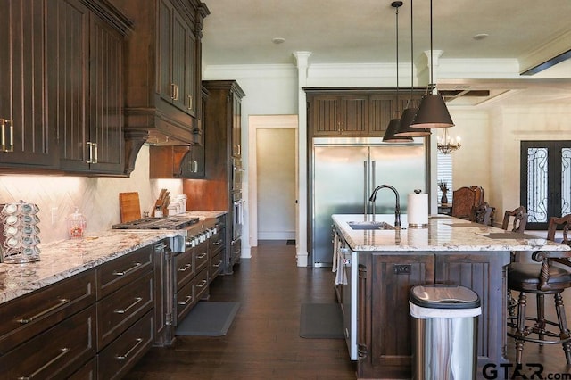 kitchen with sink, decorative light fixtures, a kitchen breakfast bar, an island with sink, and stainless steel appliances