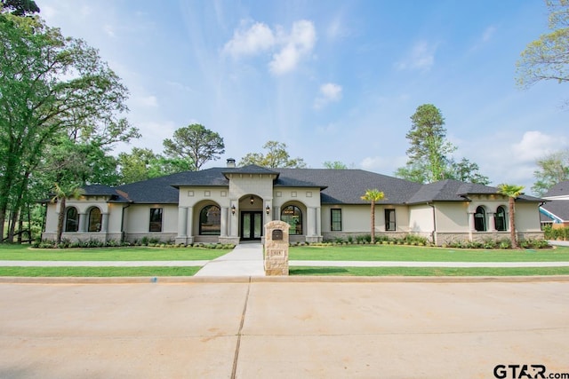 view of front facade featuring french doors, a front yard, and stucco siding