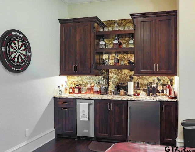 bar featuring backsplash, dark wood-type flooring, light stone countertops, and refrigerator