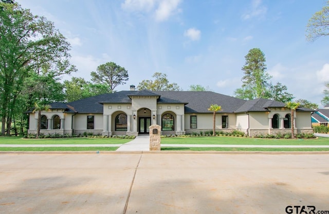 view of front of property featuring a shingled roof, a front yard, a chimney, and stucco siding