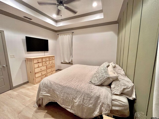 bedroom featuring a tray ceiling, light hardwood / wood-style flooring, and ceiling fan