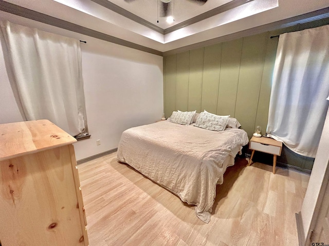 bedroom featuring light hardwood / wood-style floors and a raised ceiling