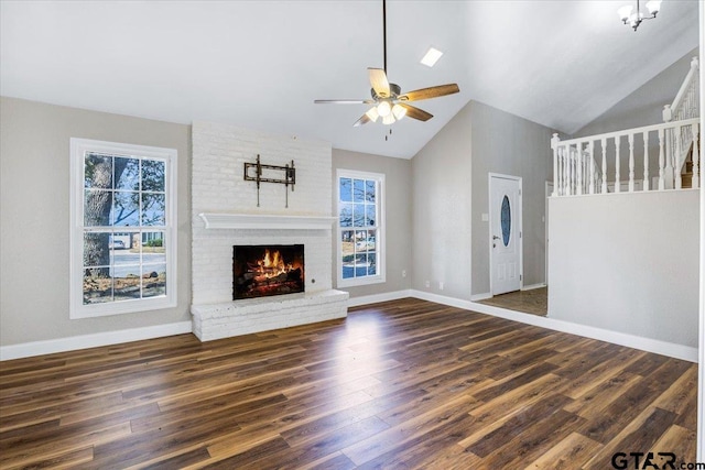 unfurnished living room featuring plenty of natural light, dark hardwood / wood-style floors, a fireplace, and ceiling fan