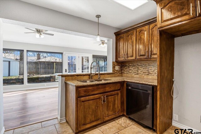 kitchen with dishwasher, backsplash, sink, light stone counters, and kitchen peninsula