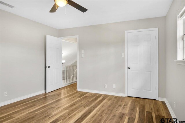 unfurnished bedroom featuring multiple windows, ceiling fan, and hardwood / wood-style floors