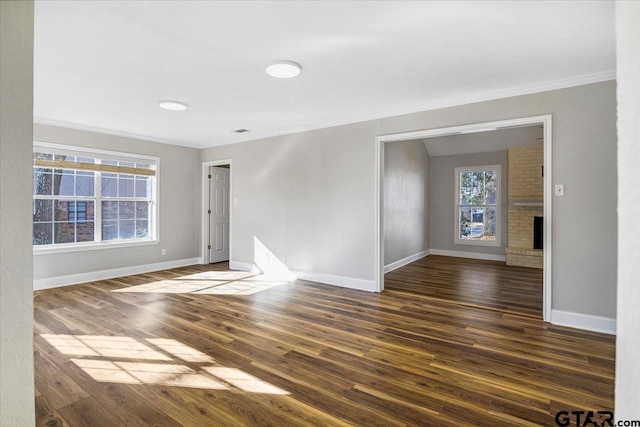 unfurnished room with a fireplace, dark wood-type flooring, plenty of natural light, and ornamental molding