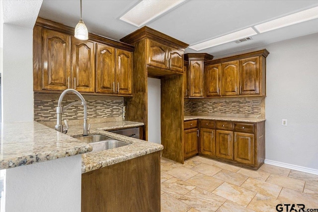 kitchen featuring decorative backsplash, light stone countertops, sink, and kitchen peninsula