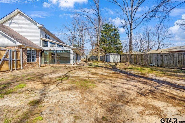 view of yard featuring a sunroom and a storage unit