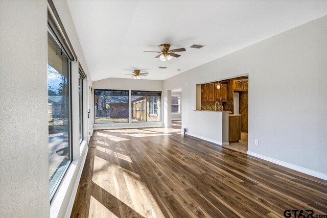 unfurnished living room featuring dark hardwood / wood-style floors, vaulted ceiling, ceiling fan, and sink