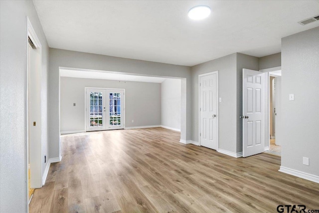 unfurnished living room featuring french doors and light hardwood / wood-style flooring