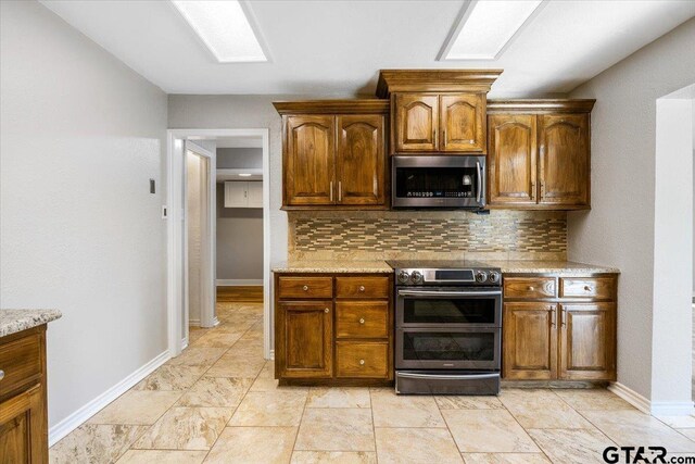 kitchen with tasteful backsplash, light stone counters, and appliances with stainless steel finishes