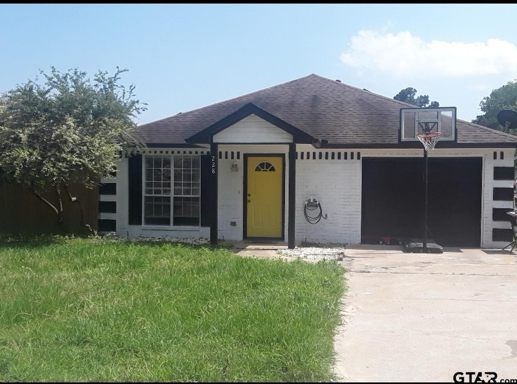 ranch-style house featuring a garage and a front lawn