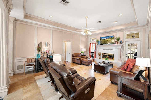 living area featuring a fireplace, a raised ceiling, visible vents, and a decorative wall