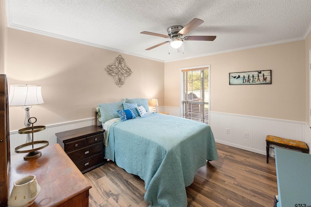 bedroom with a wainscoted wall, dark wood-style floors, and a textured ceiling